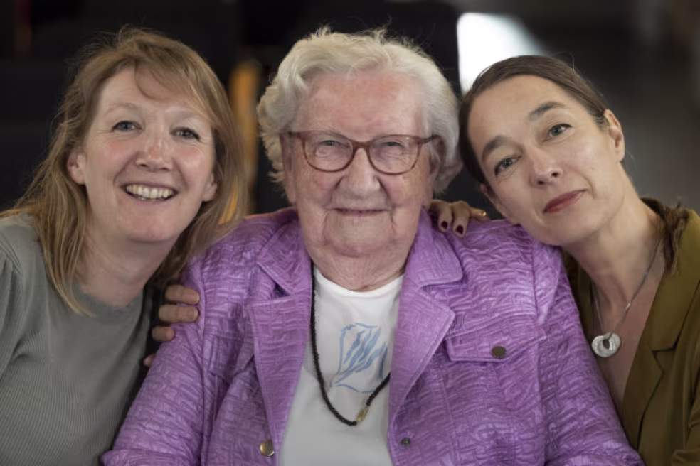 Familiefoto met drie generaties toont liefdevolle verbondenheid en steun in het kader van be-wonder en generatieoverstijgende zorg