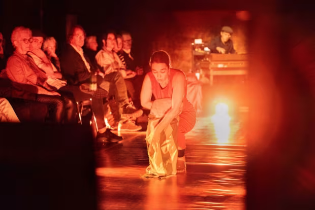Theaterscène met theatrale uitvoering en warme oranje verlichting, aanwezige toeschouwers, theater, dans, film en oral-history